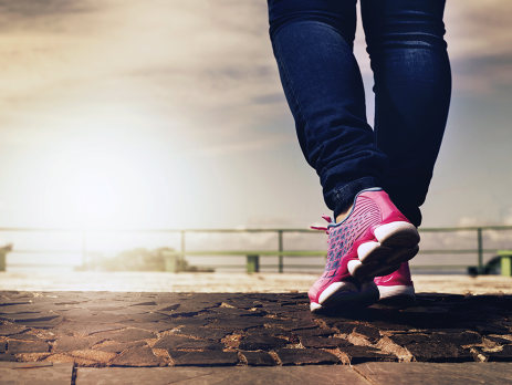 a shot of a person from the knees down, wearing jeans and athletic shoes