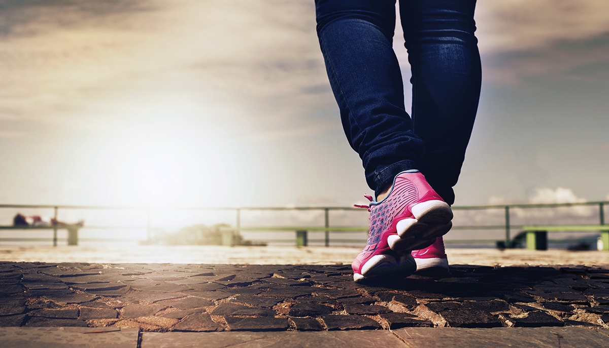 a shot of a person from the knees down, wearing jeans and athletic shoes