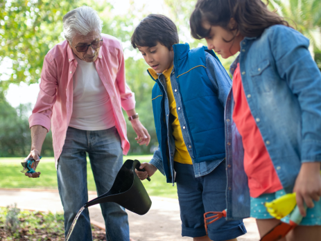 grandfather and grandchildren watering a garden