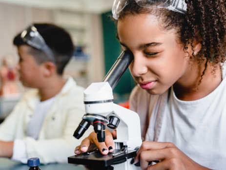 young girl looks into a microscope