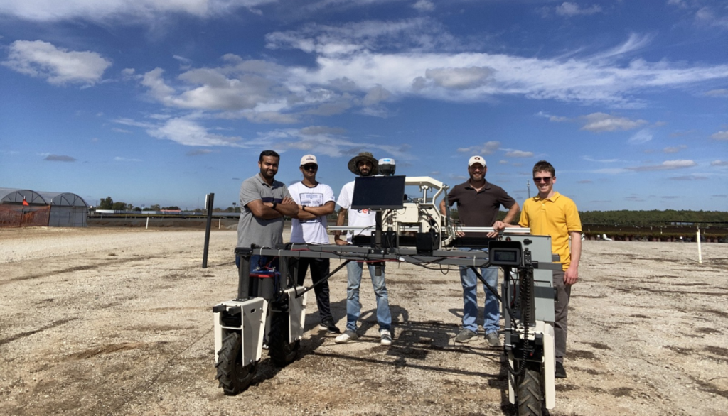 a group of scientists smile around the AI-powered robot in an experimental field