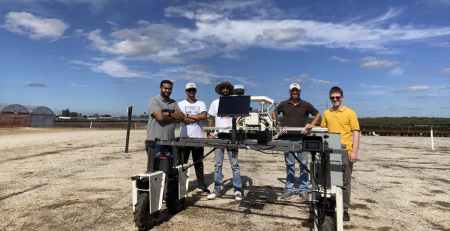 a group of scientists smile around the AI-powered robot in an experimental field