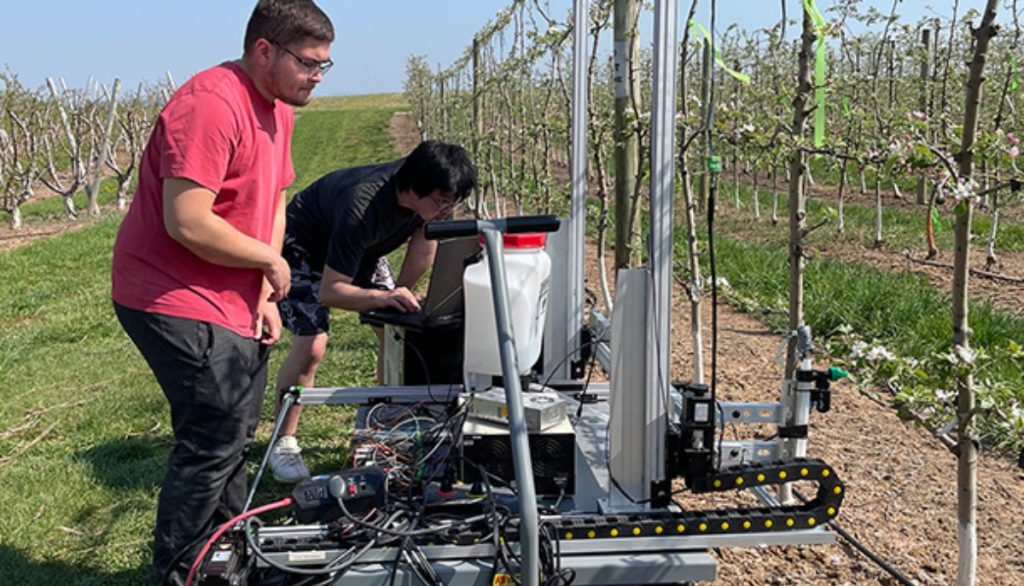 two scientists operate a robotic apple blossom sprayer