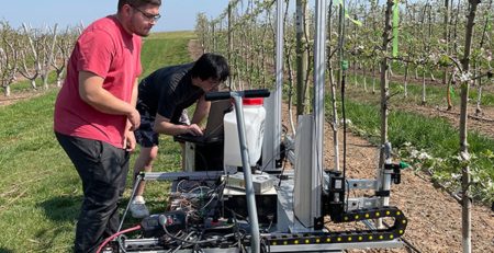 two scientists operate a robotic apple blossom sprayer