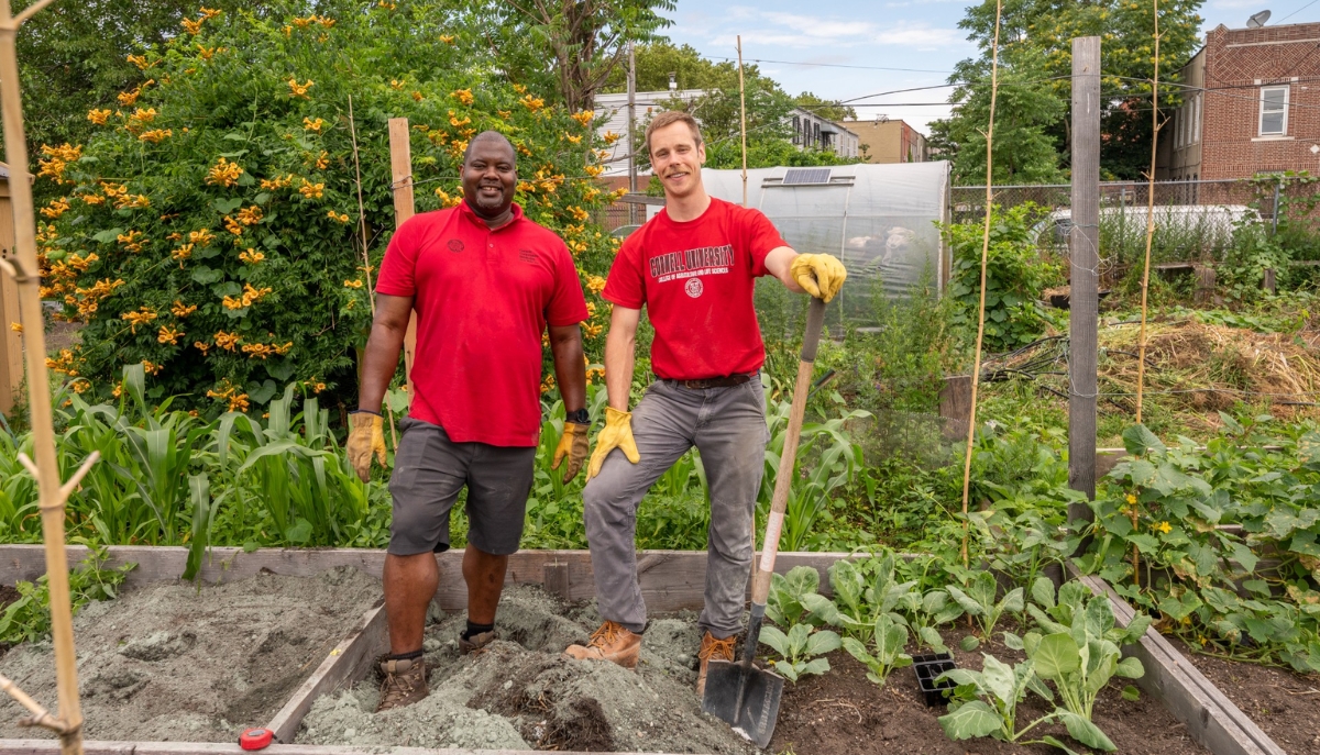 two smiling Extension agents in a community garden