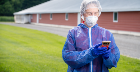 a person wearing PPE and looking at a device
