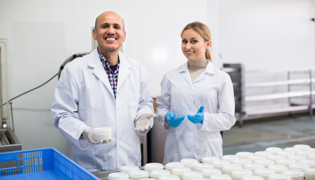 two scientists smile next to samples of dairy byproducts