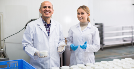 two scientists smile next to samples of dairy byproducts