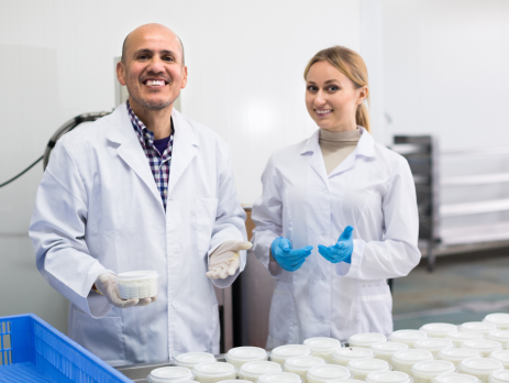 two scientists smile next to samples of dairy byproducts