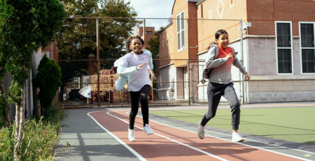 two young teens running on a school track