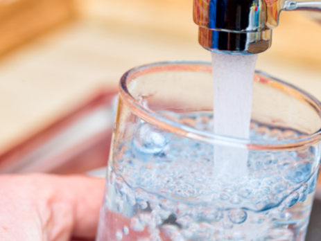 cup being filled with water from a sink tap