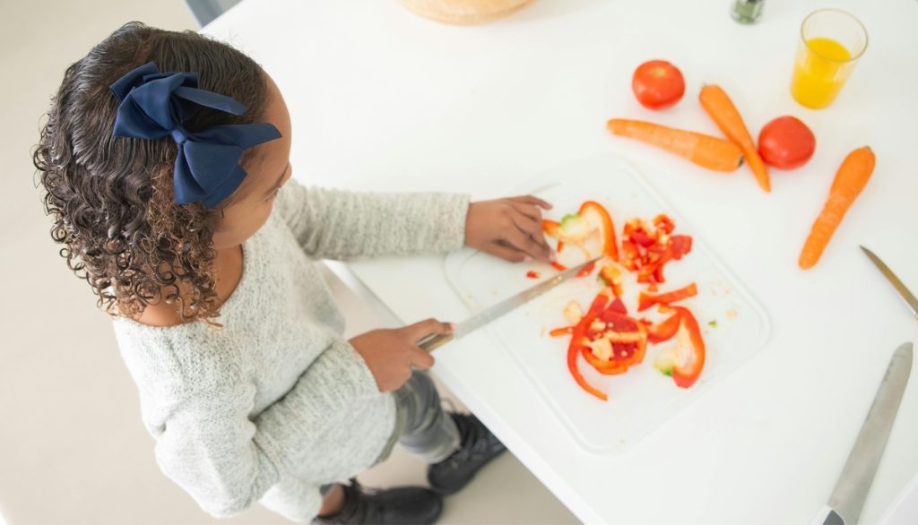 girl slicing a pepper and other vegetables