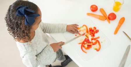 girl slicing a pepper and other vegetables