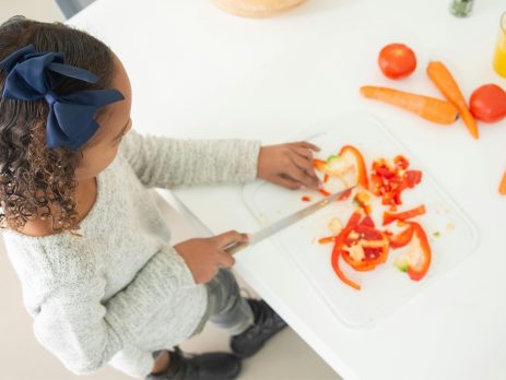 girl slicing a pepper and other vegetables