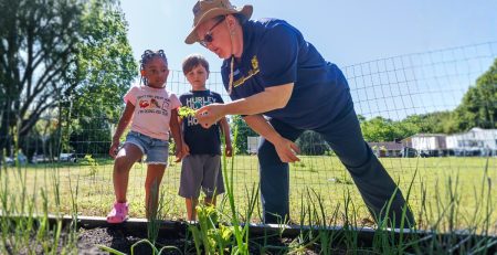 an Extension agent shows youths plants from a community garden