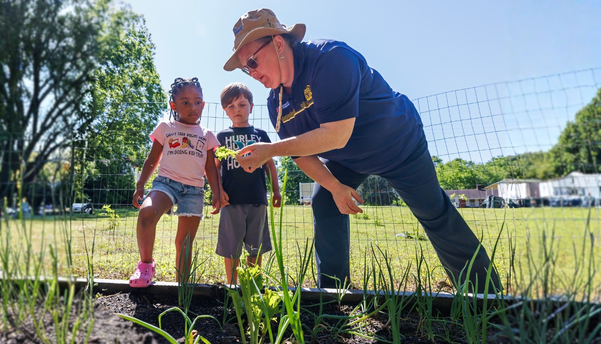 an Extension agent shows youths plants from a community garden
