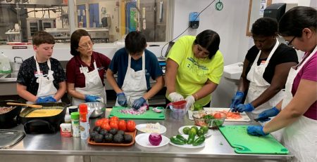 a group of youth and an instructor cook in an industrial kitchen
