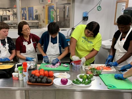 a group of youth and an instructor cook in an industrial kitchen
