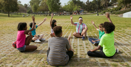 a group of campers sit in a circle with their hands raised