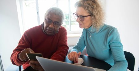 a woman helps a senior man on the computer