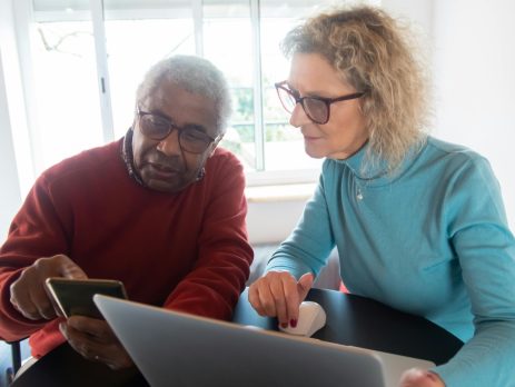 a woman helps a senior man on the computer