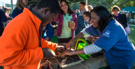 a 4-h leader helps a participant with a planting