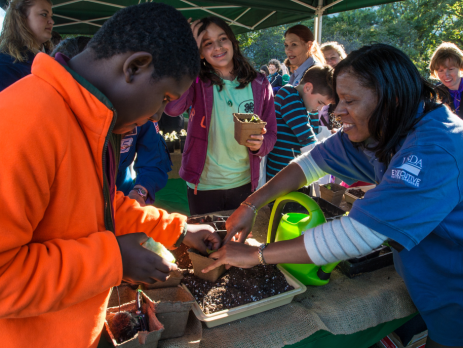 a 4-h leader helps a participant with a planting