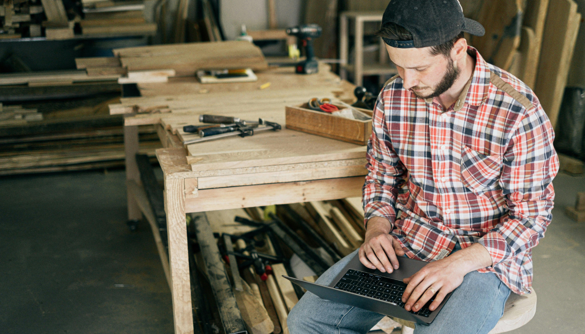 a person in woodworking shop works at a laptop