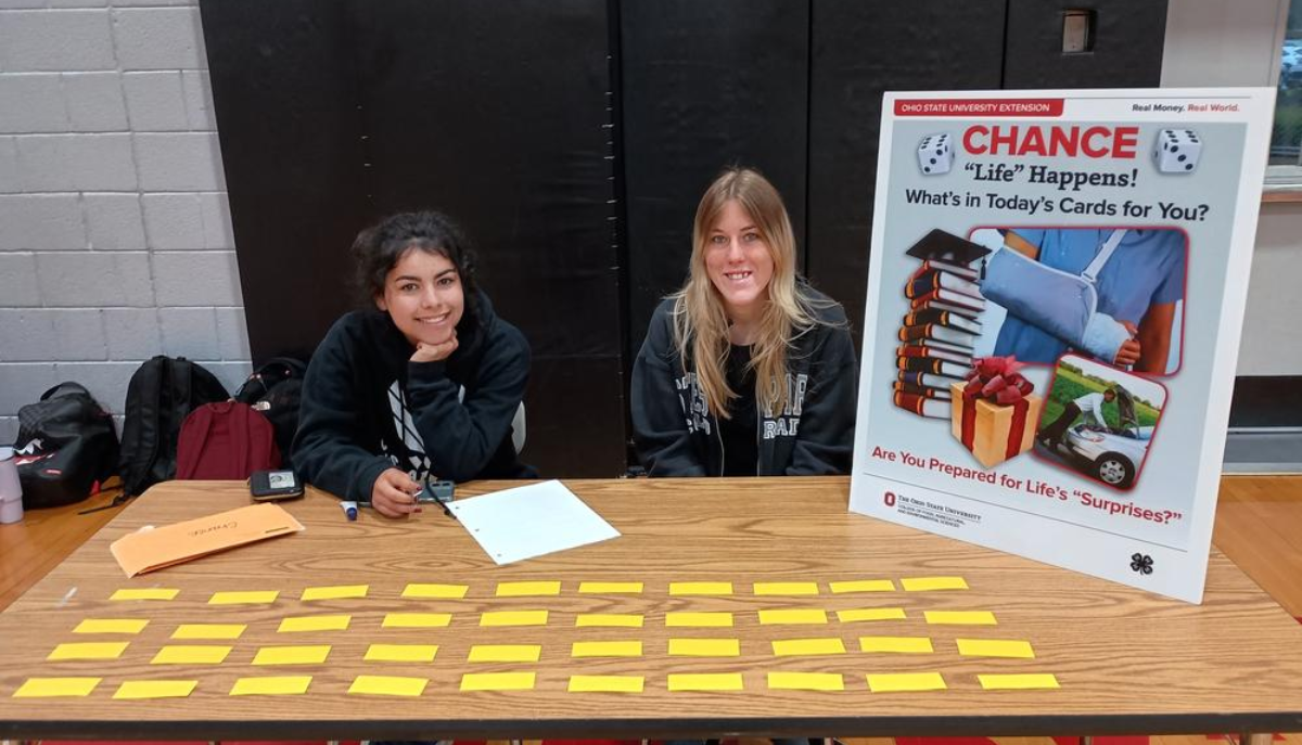 two girls sitting at a table with information