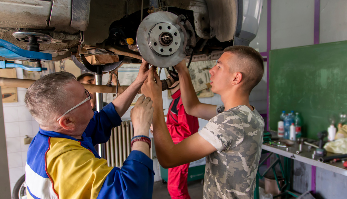 an adult and teen work on a car