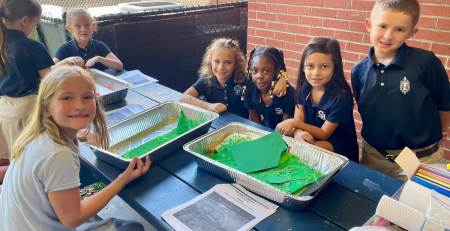 a group of children smile around a science experiment