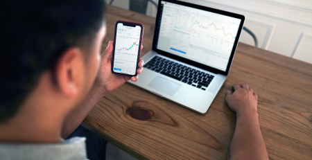 a person looks at information on their phone and laptop