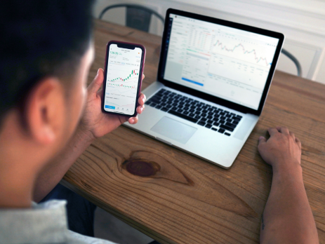 a person looks at information on their phone and laptop