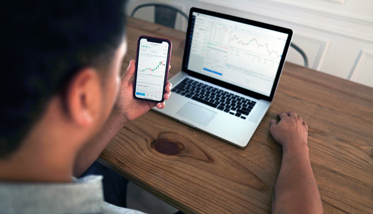 a person looks at information on their phone and laptop